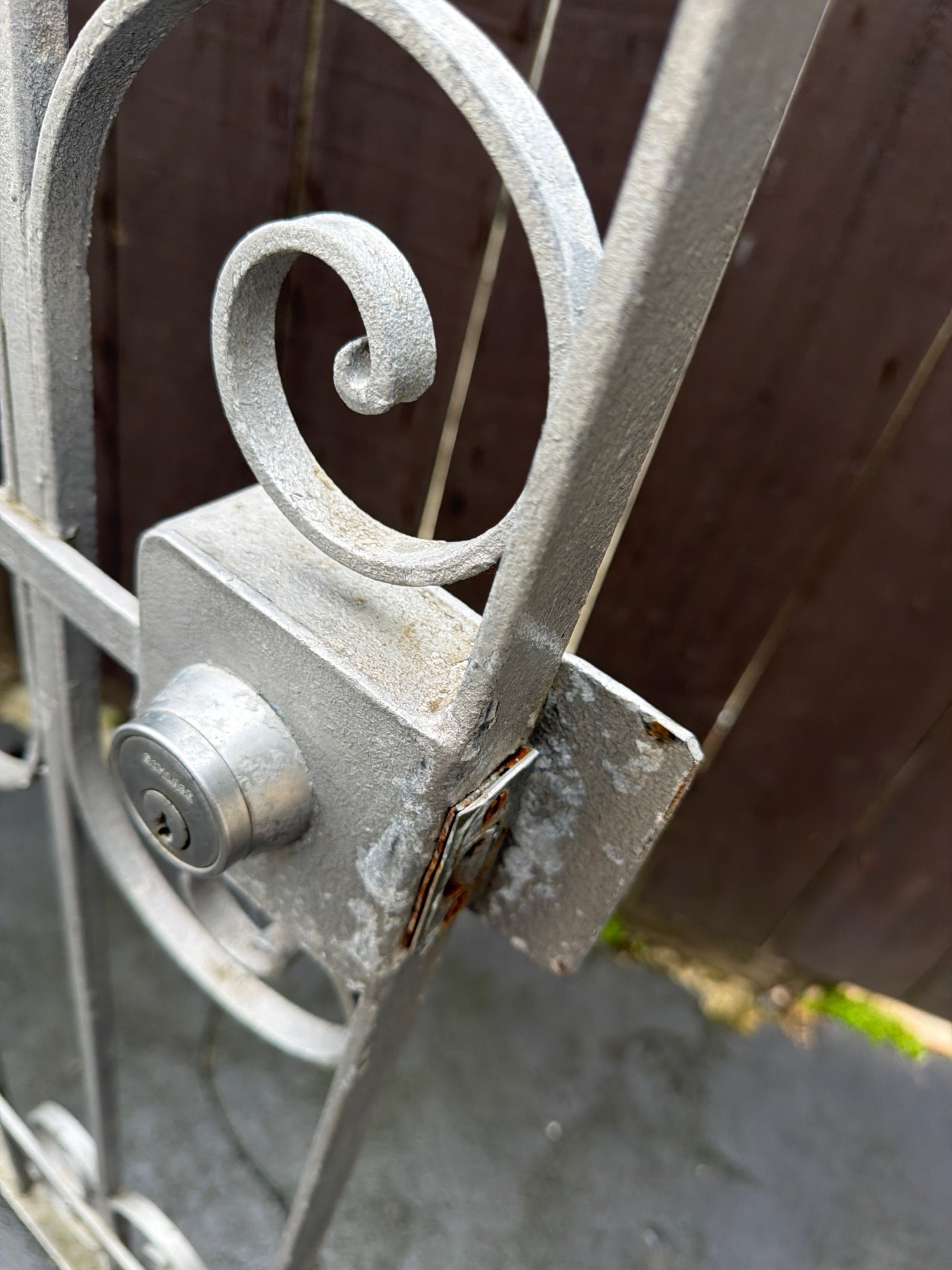 Rekeyed deadbolt on a wrought iron gate with keypad-style scrollwork