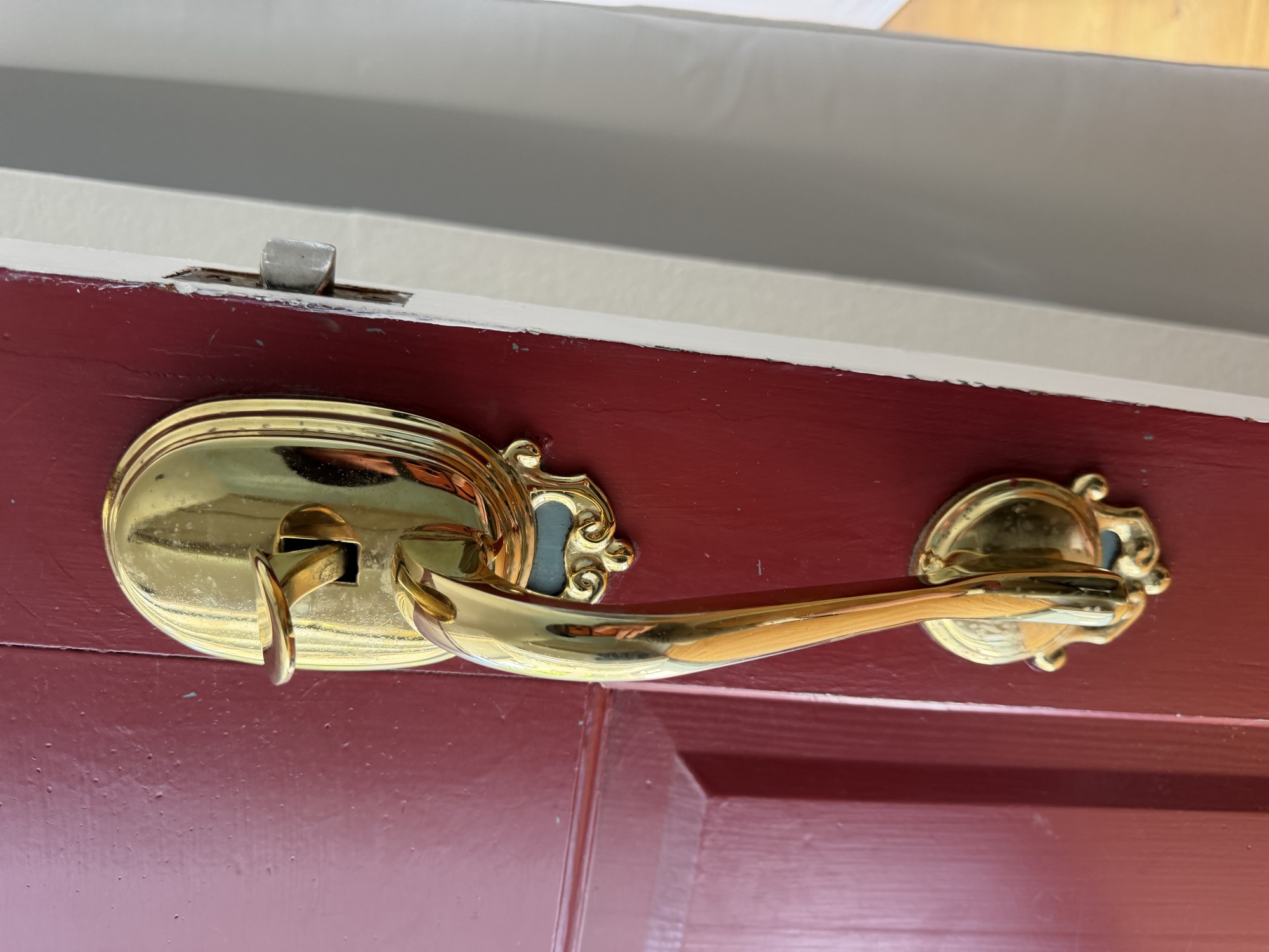 Polished brass door knob and deadbolt handleset on a maroon front door