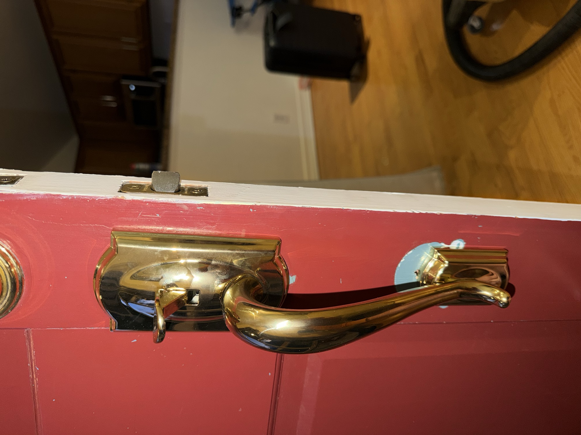 Brass entry door handleset with deadbolt and lever on a red door