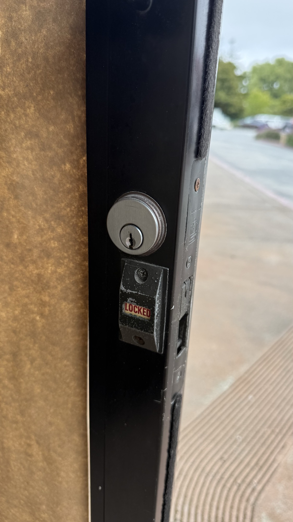 Rekeyed deadbolt with locked indicator on a black storefront door frame