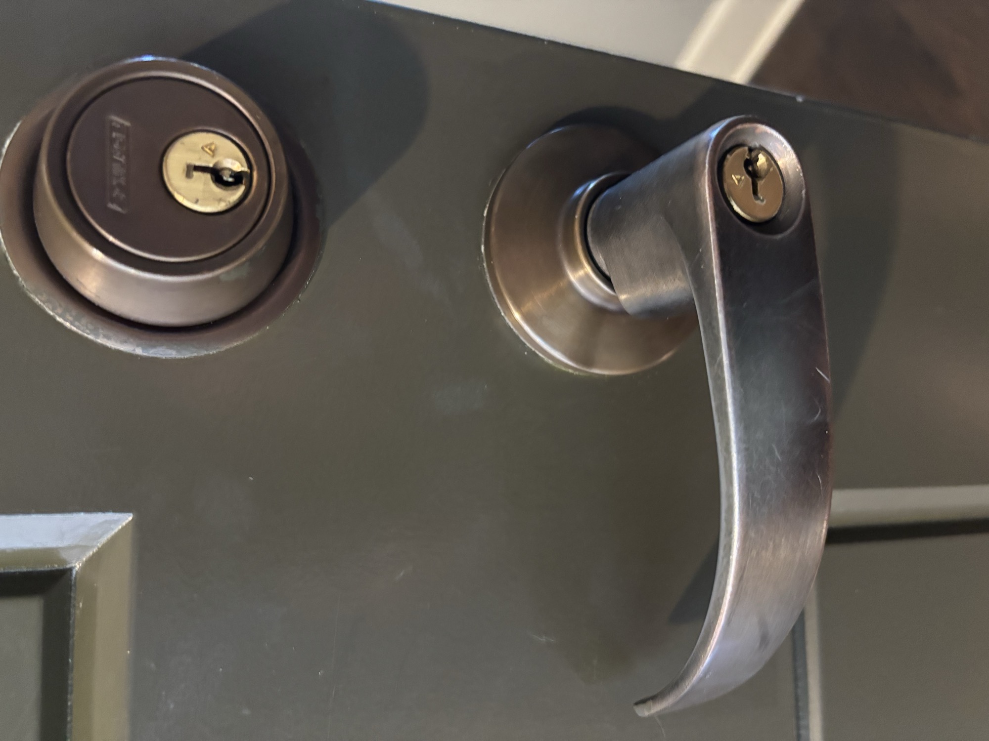 Rekeyed deadbolt and door lever installed on a dark commercial door